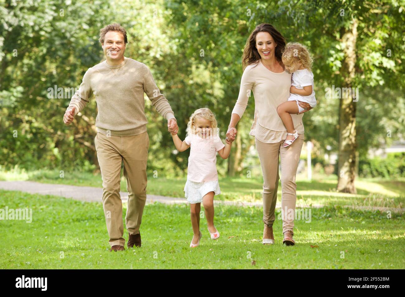 Portrait d'une jeune famille heureuse de quatre personnes marchant ensemble le parc Banque D'Images