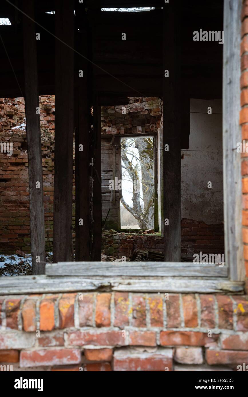 l'intérieur d'un bâtiment abandonné en brique rouge s'est effondré à travers une vieille fenêtre en bois. la vue vous mène à la fenêtre opposée, à travers laquelle vous pouvez s. Banque D'Images
