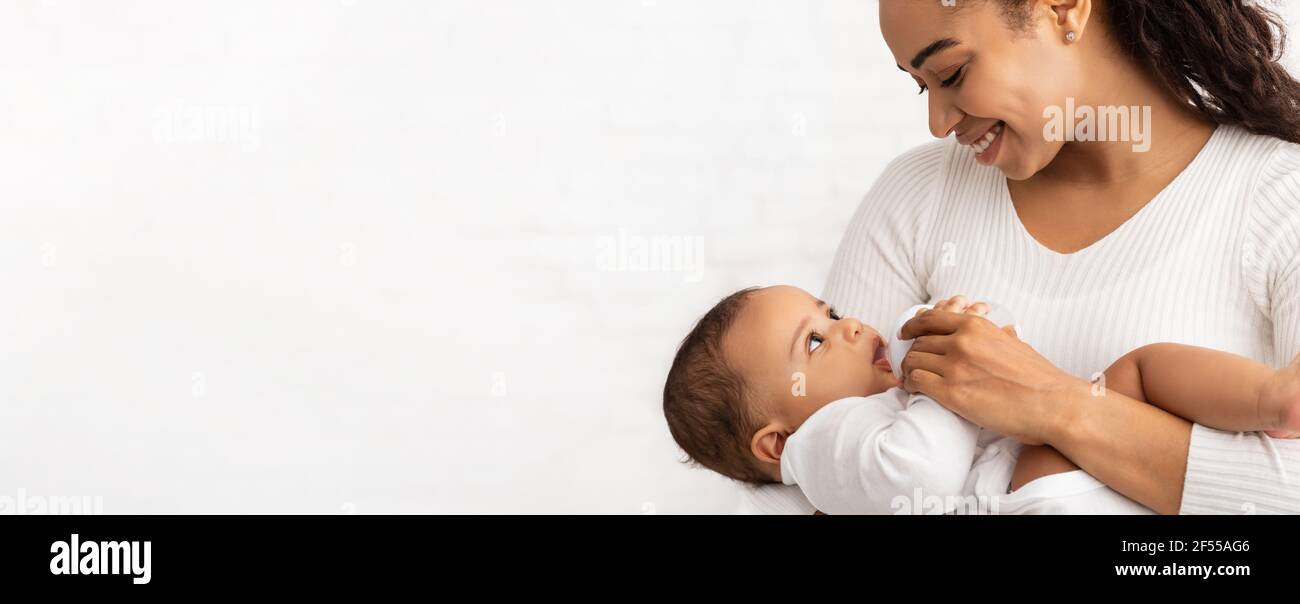 Mère africaine nourrissant bébé debout sur fond blanc, Panorama, Cropped Banque D'Images