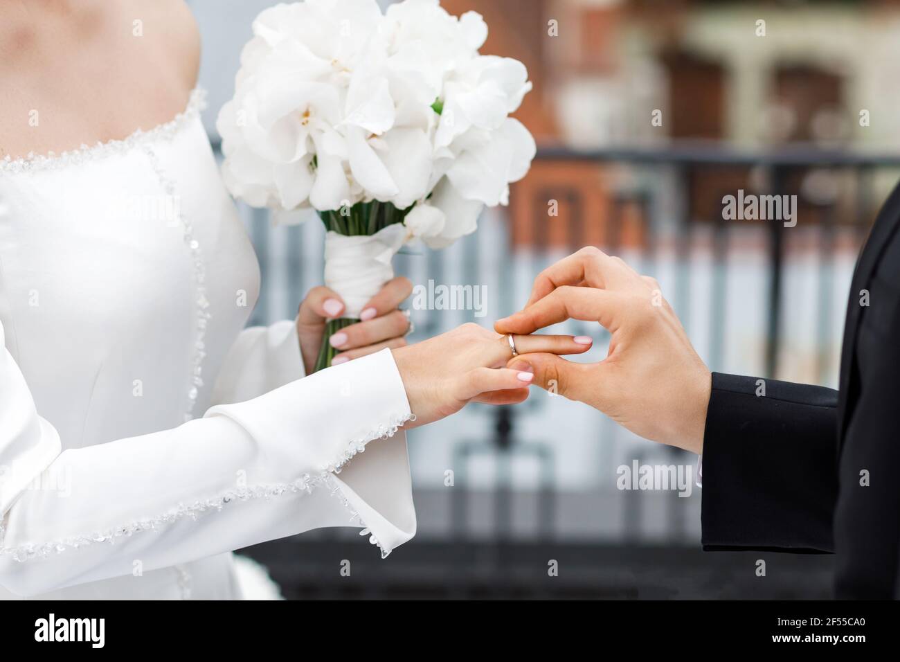 Couple en anneaux d'échange de vêtements de mariage avec un bouquet de fleurs dans l'église. Banque D'Images