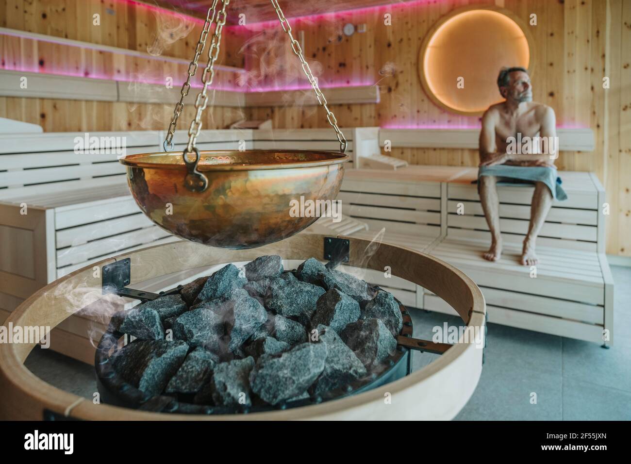 Homme regardant loin en s'asseyant dans le sauna finlandais Banque D'Images