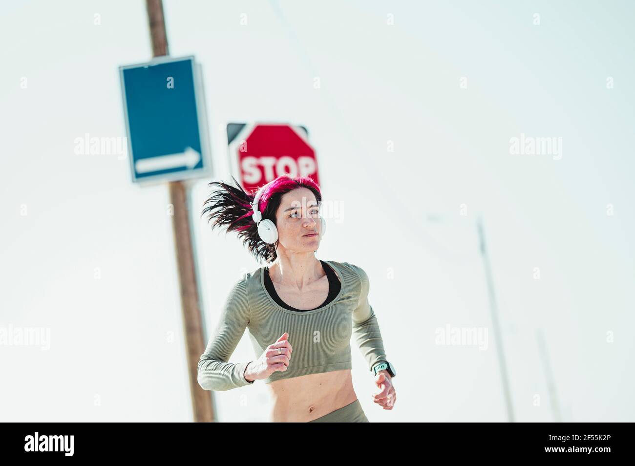 Femme avec un casque regardant loin en courant contre le panneau d'affichage Banque D'Images