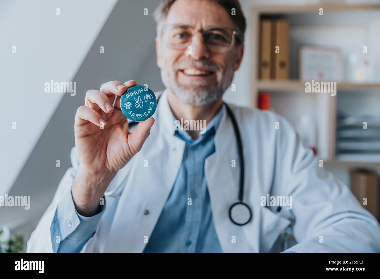 Un médecin souriant tenant l'insigne du signe de la paix en se tenant debout clinique Banque D'Images