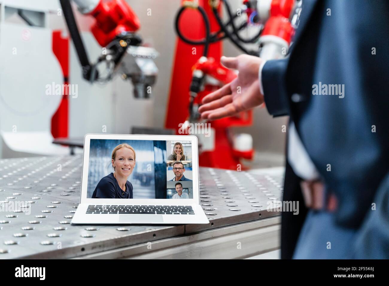 Un ingénieur en automatisation fait des gestes tout en discutant sur appel vidéo ordinateur portable en usine Banque D'Images