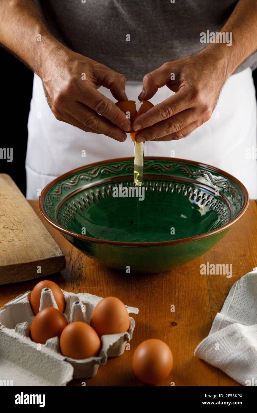 Section centrale de l'homme craquant l'œuf de poulet dans le bol Banque D'Images