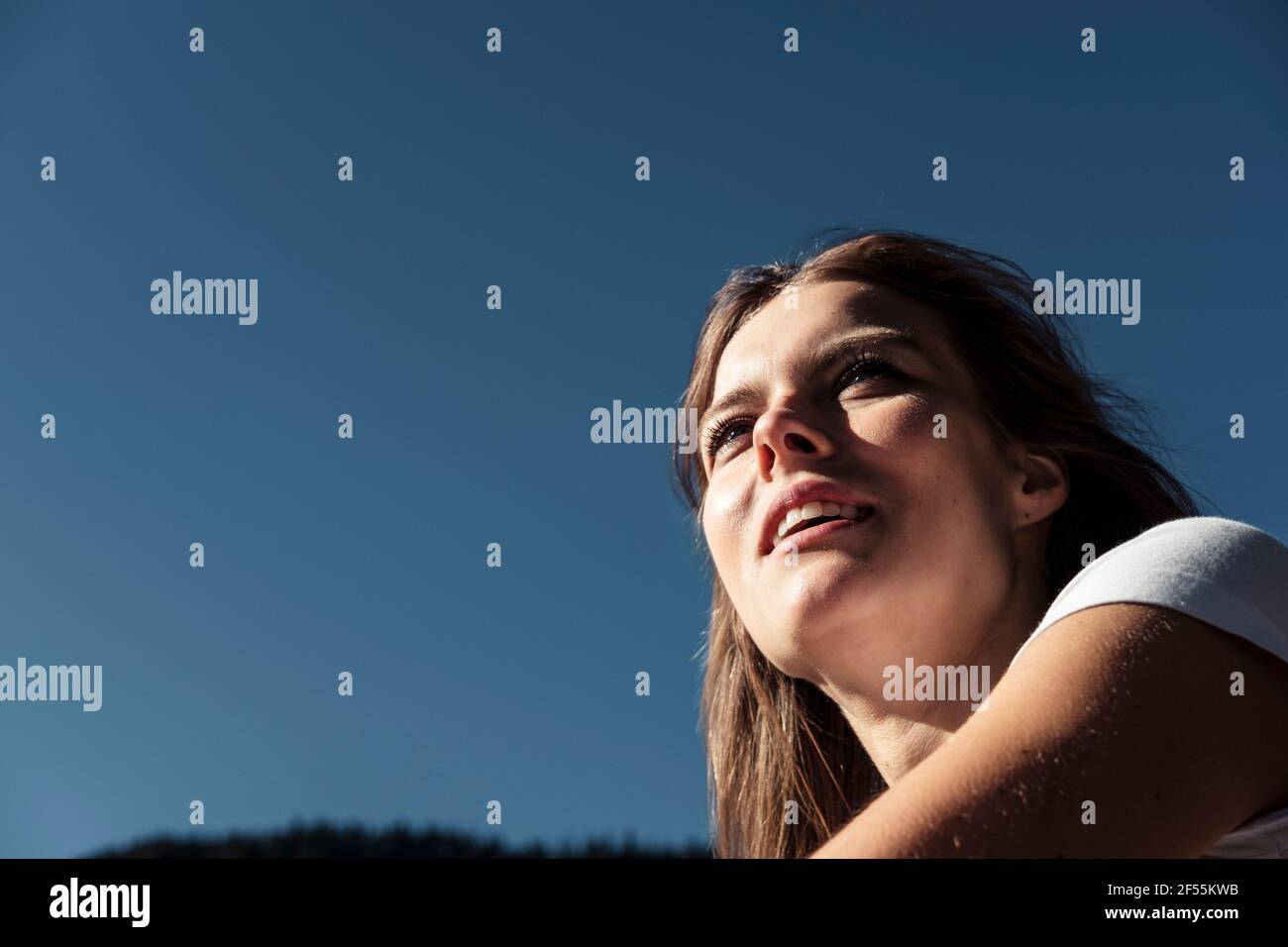 Jeune femme souriante regardant loin contre le ciel bleu Banque D'Images