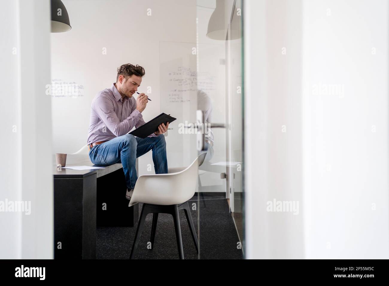 Un homme d'affaires remue-méninges en regardant le presse-papiers au bureau Banque D'Images
