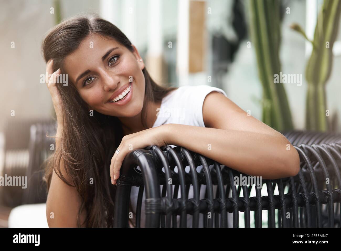 Gros plan en plein air belle femme portugaise toucher cheveux flirty sourire tête inclinable en profitant d'une conversation animée et intéressante terrasse de café Banque D'Images