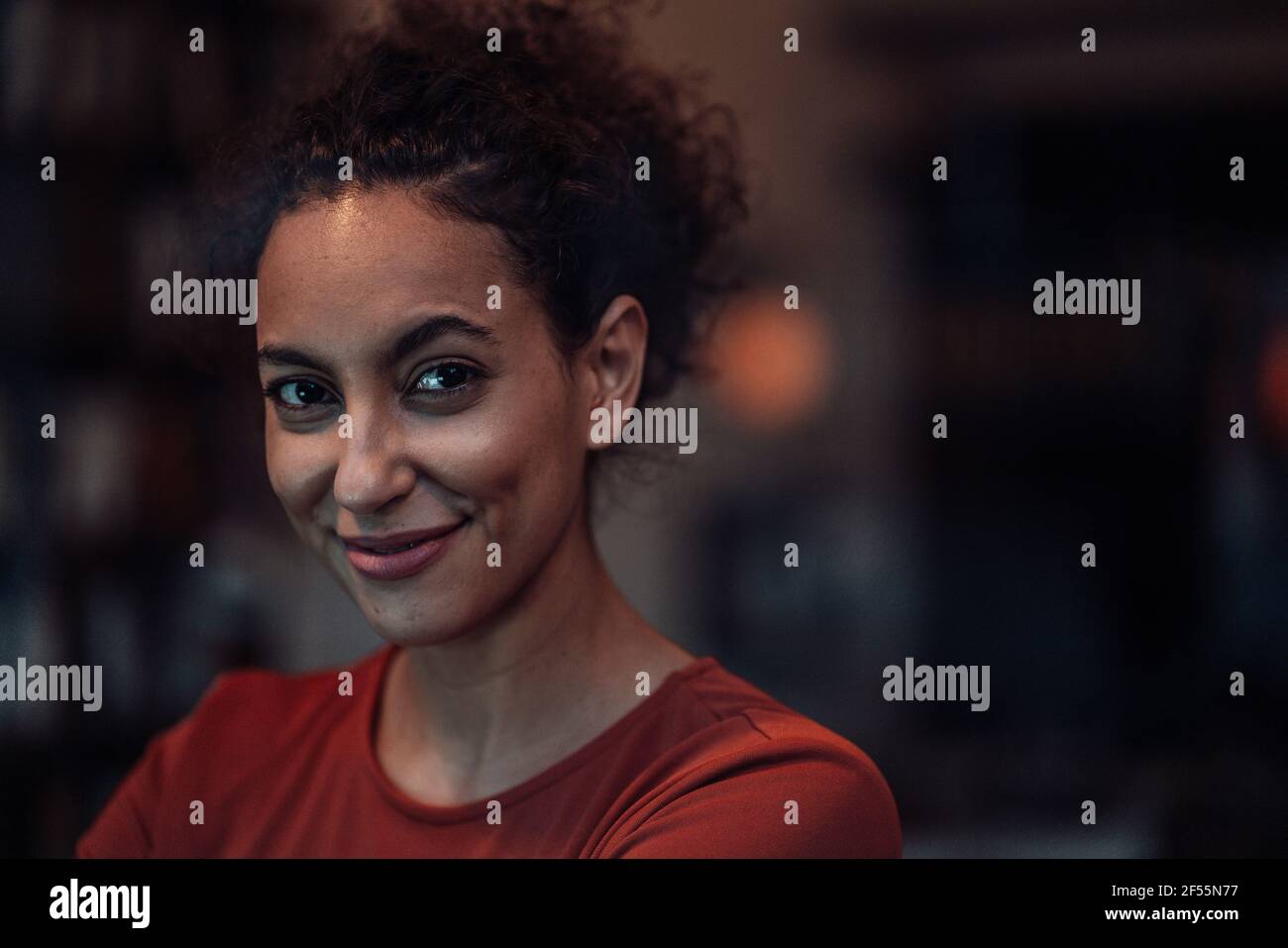 Femme souriante regardant pendant qu'elle est assise au café Banque D'Images