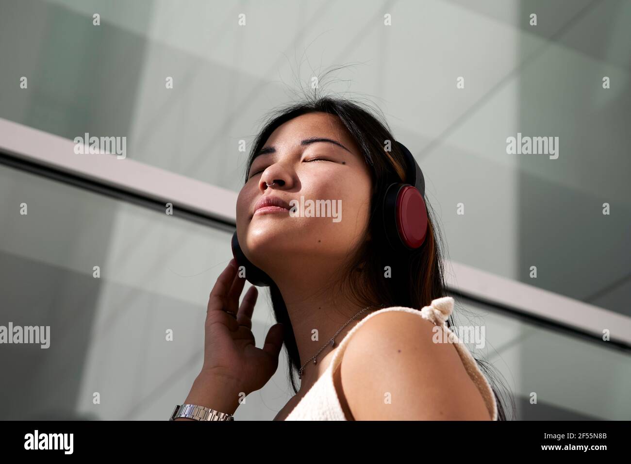 Femme asiatique écoutant de la musique à travers des écouteurs en extérieur Banque D'Images