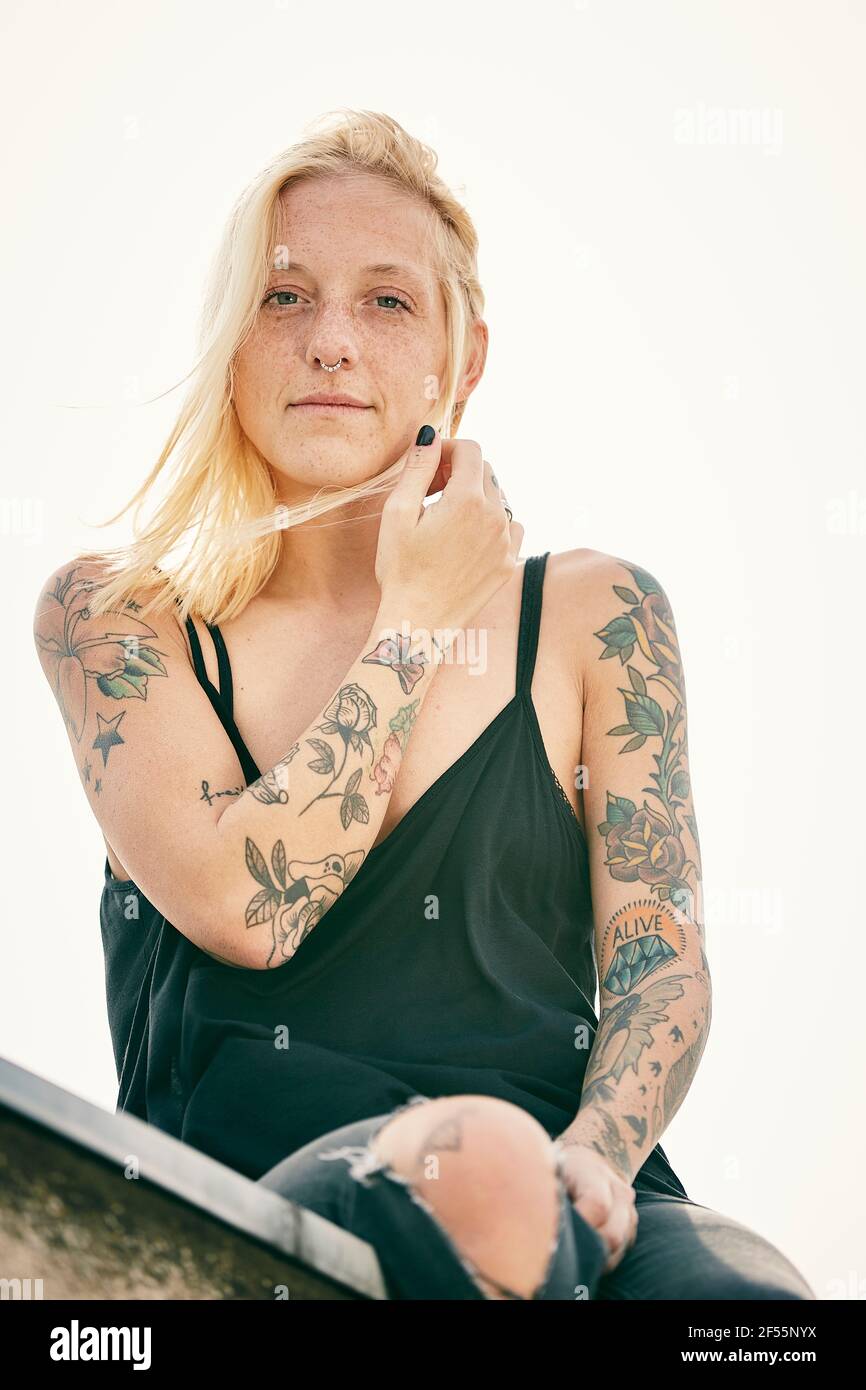 Femme blonde avec tatouage assis sur le toit Banque D'Images