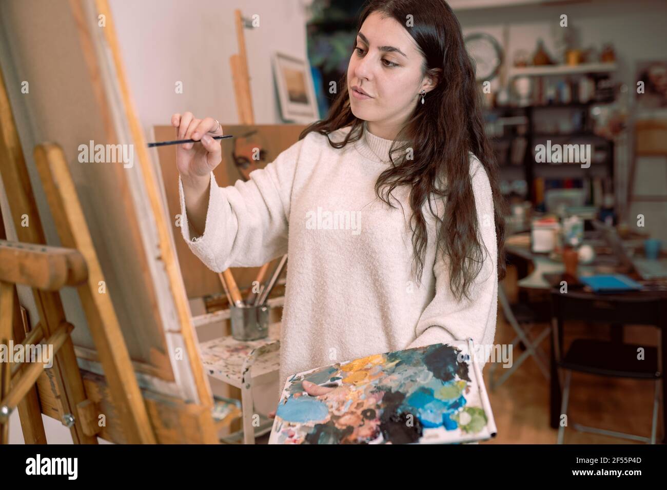 Artiste féminine peignant sur toile au studio d'art Banque D'Images