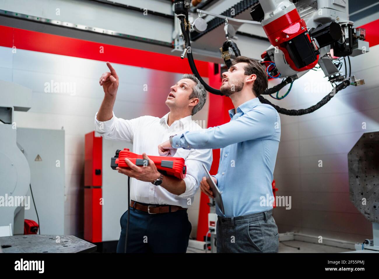 Les ingénieurs masculins examinent la robotique en usine Banque D'Images