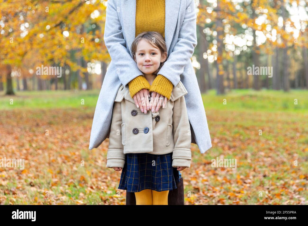 Femme portant une veste debout avec le bras autour de la fille dans la forêt Banque D'Images