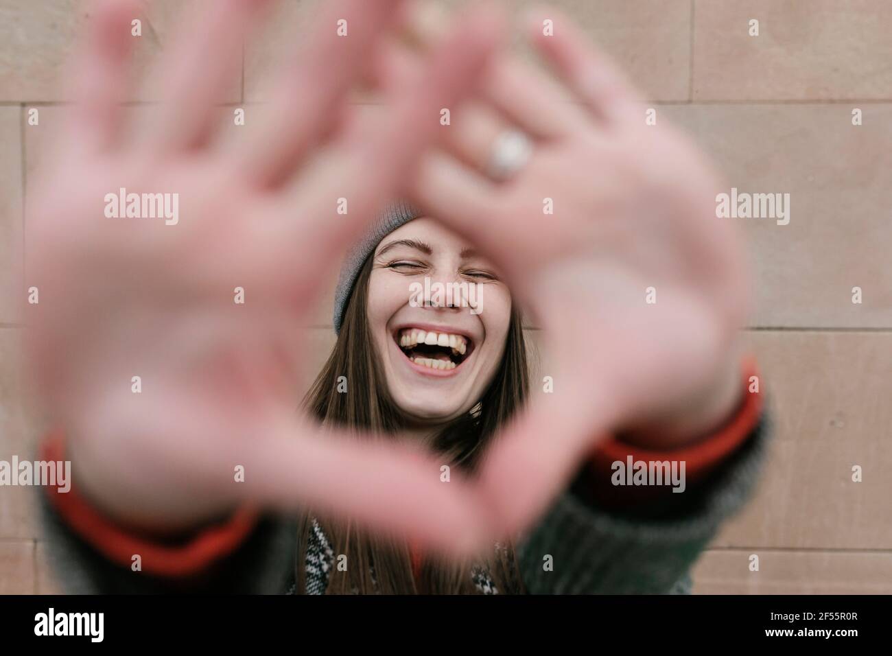 Rire belle femme vue par les mains contre le mur Banque D'Images