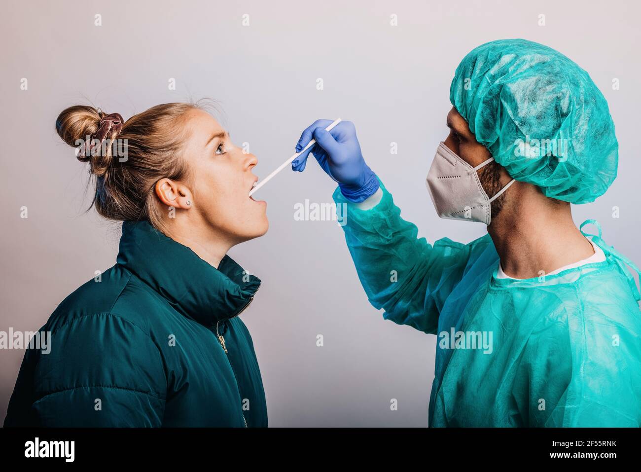 Expertise en matière d'examen de la gorge d'un patient féminin, debout contre le gris arrière-plan Banque D'Images