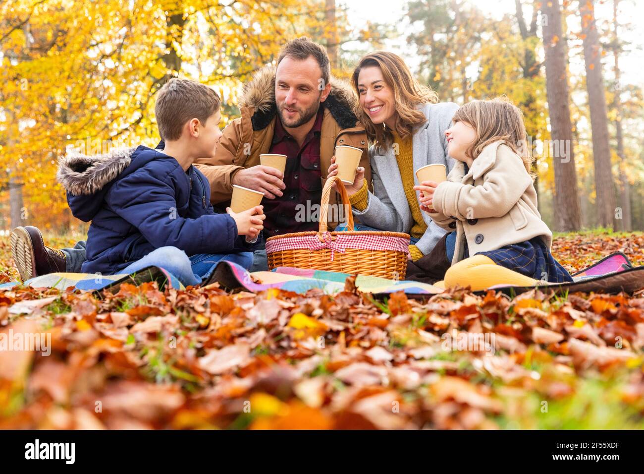 Famille souriante prenant un café ensemble en forêt Banque D'Images