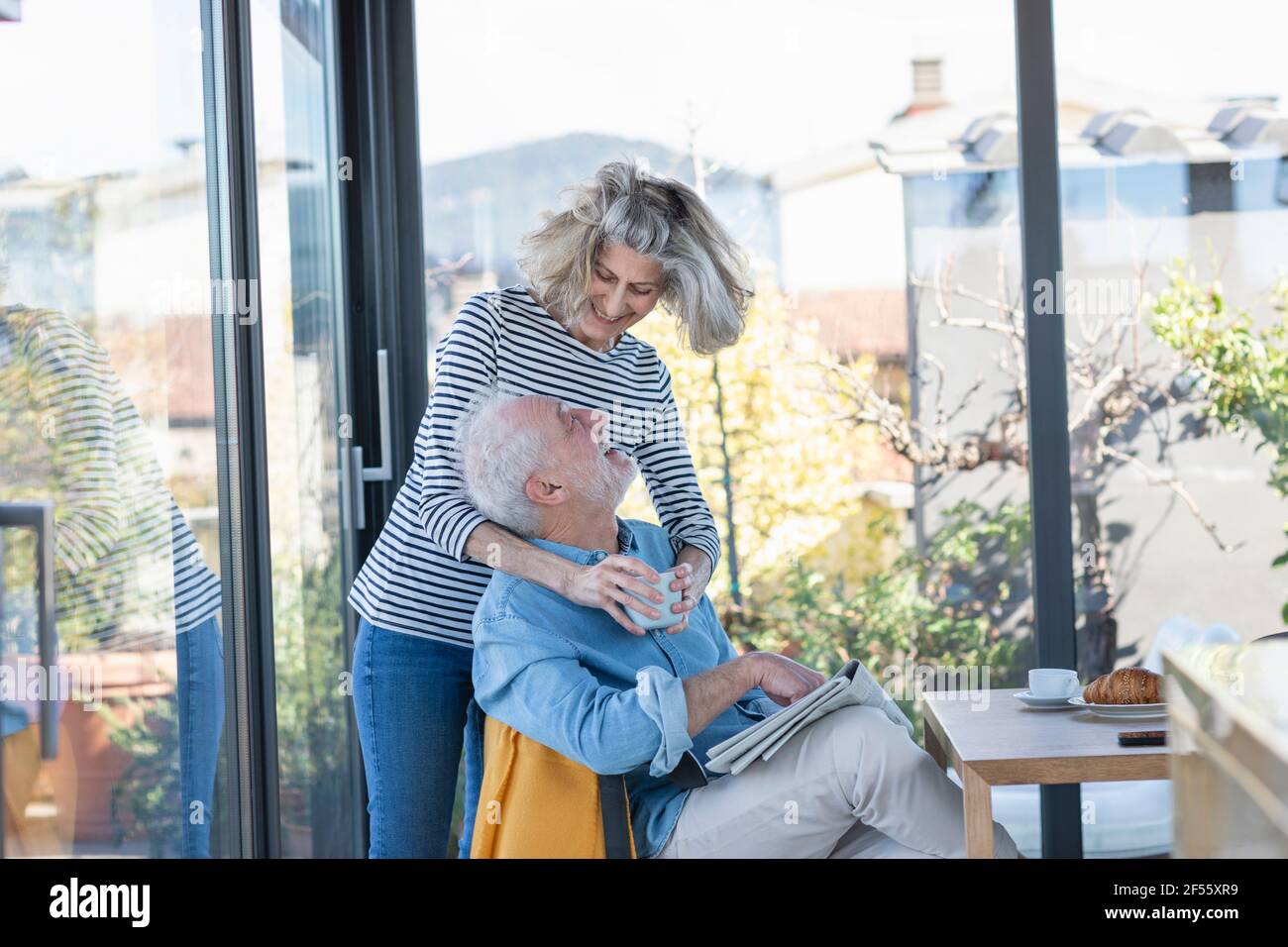 Femme souriant en se tenant debout avec le bras sur l'homme à accueil Banque D'Images