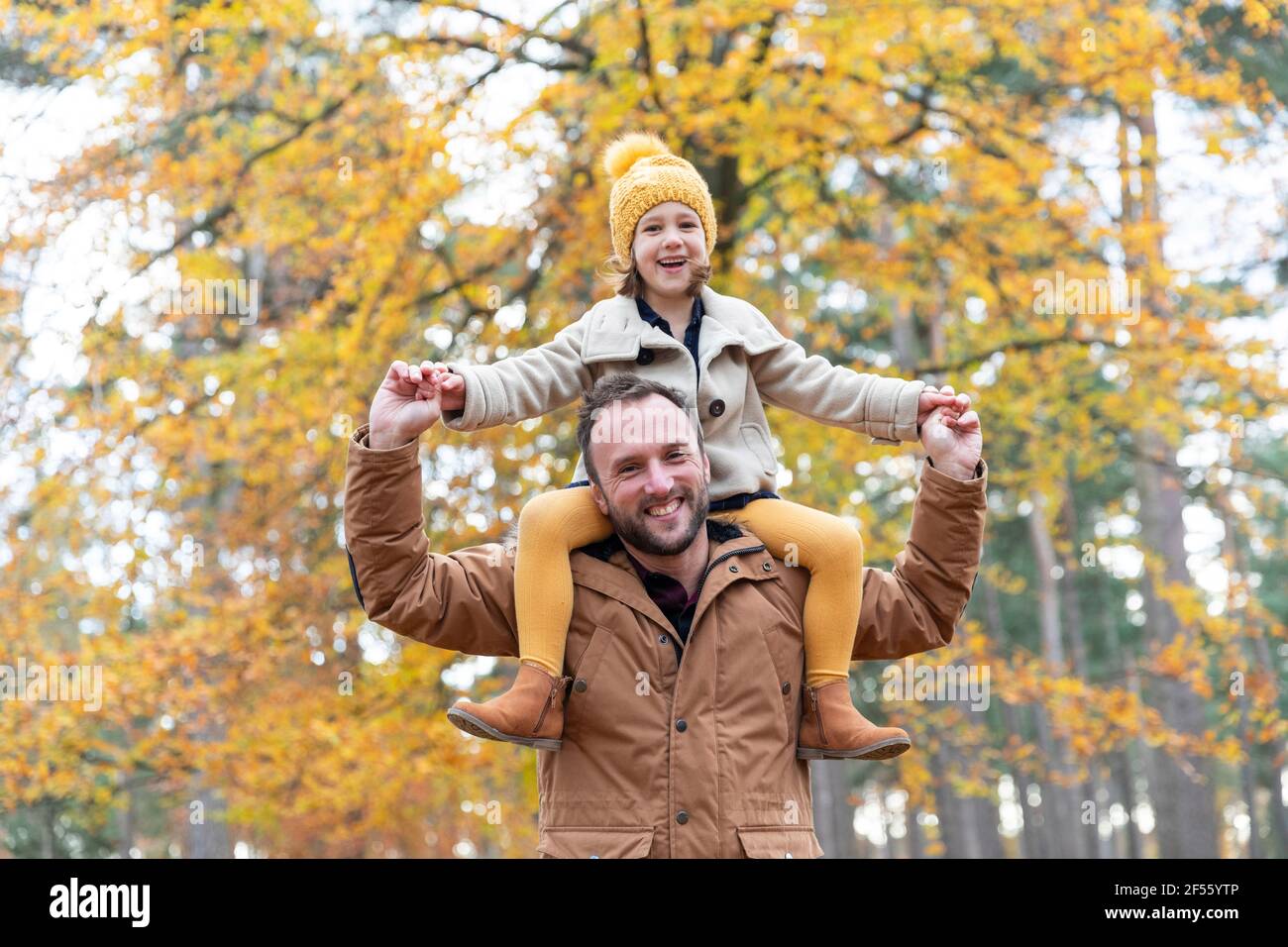 Père joueur portant une fille souriante debout dans la forêt Banque D'Images