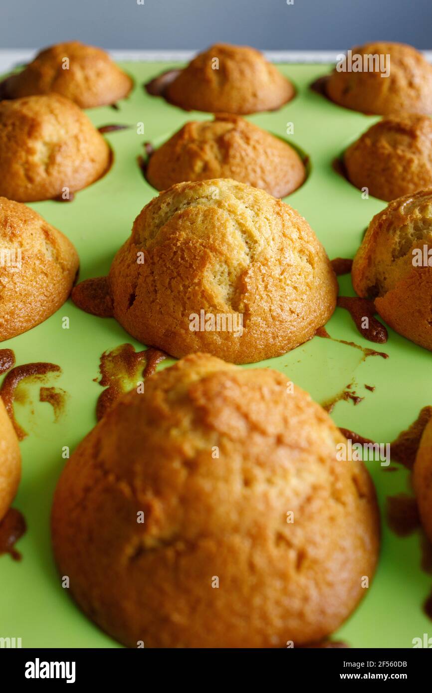 Une petite fille souriante avec un moule à muffins sur le comptoir de la cuisine Banque D'Images