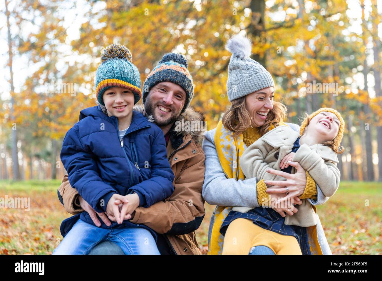 Parents souriants assis avec des enfants en forêt Banque D'Images