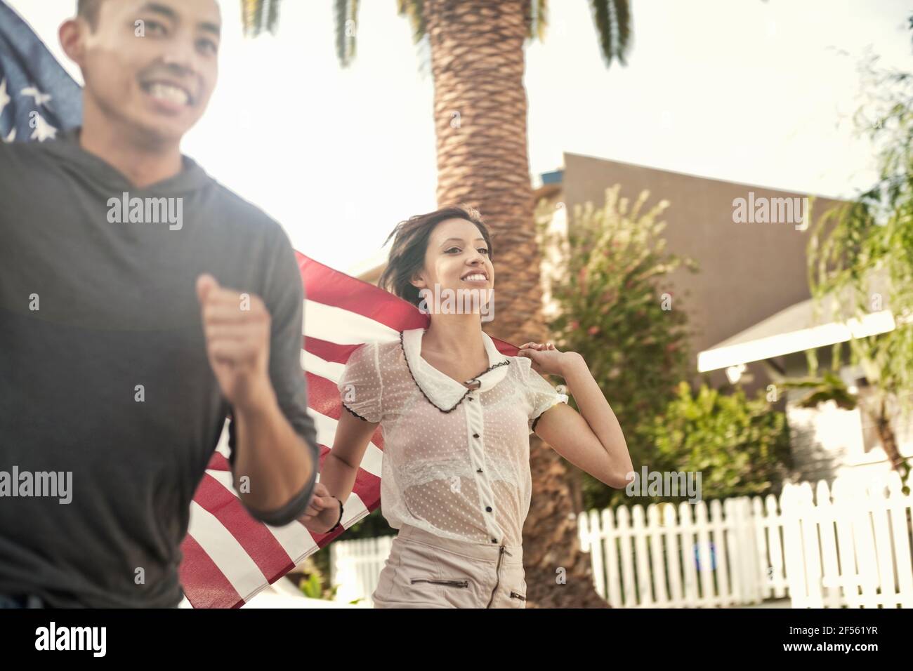 Homme et femme heureux courir avec le drapeau américain Banque D'Images