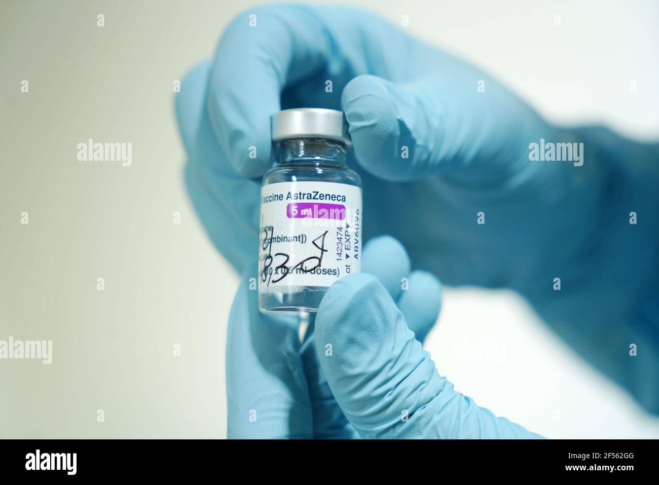 Flacon de vaccin COVID-19 produit par AstraZeneca. La main du médecin dans un gant médical tient une bouteille avec un vaccin coronavirus. Mise au point sélective. Turin, Banque D'Images