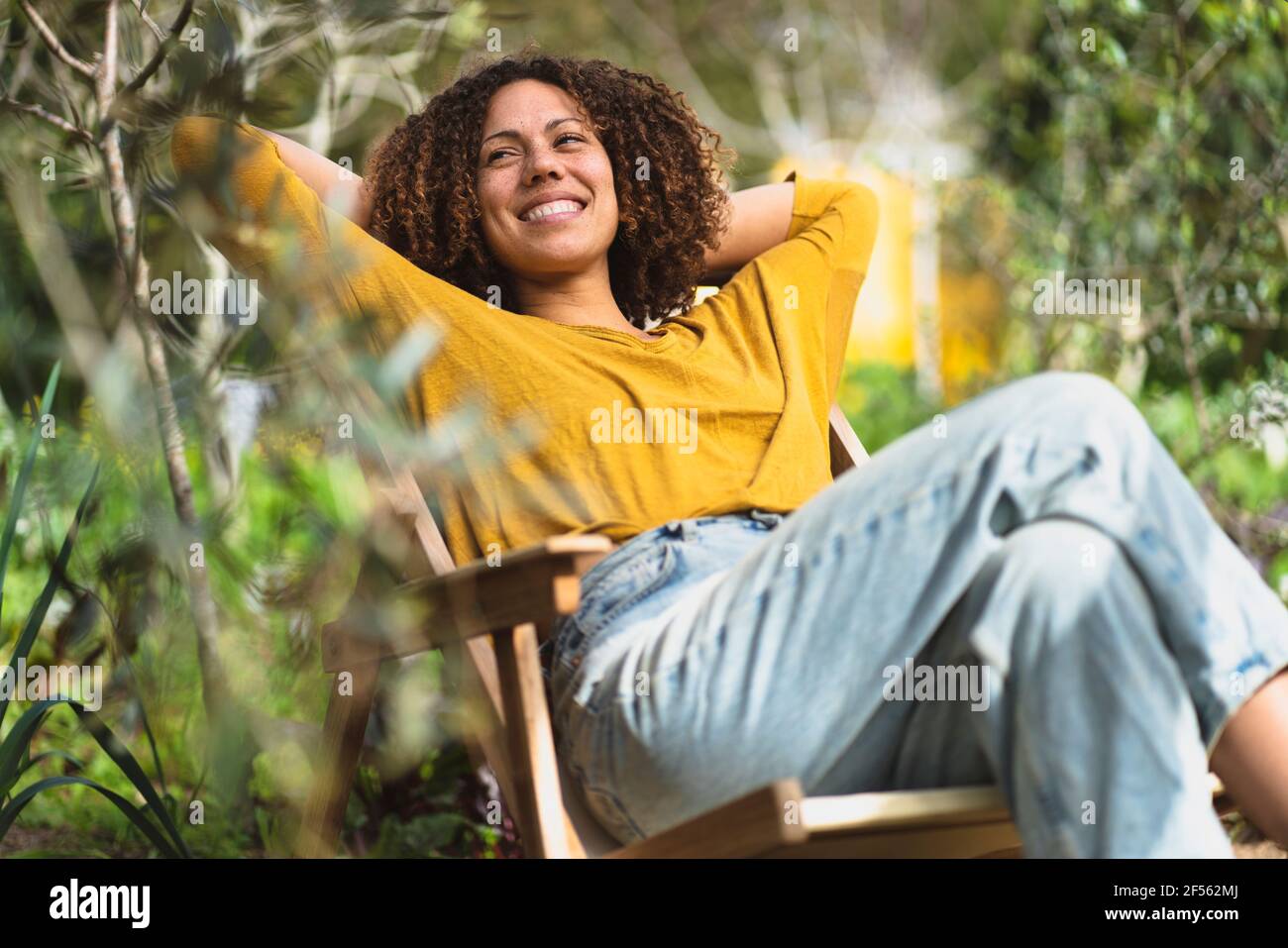 Femme souriante se détendant dans une chaise de jardin au printemps dans durable potager biologique Banque D'Images