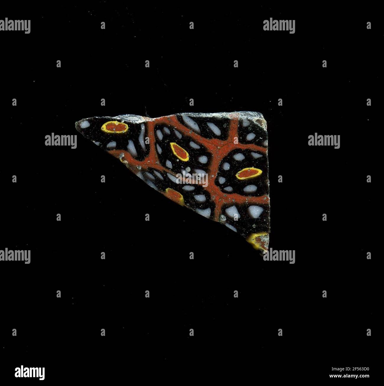 Fragment d'un vaisseau. Une faible courbure du fragment de verre permet l'affectation à un vaisseau, éventuellement à une coque. Sur une raison rouge, plusieurs fleurs peuvent être vues dans la technologie millefiori. Sur un cœur rouge avec un contour jaune, se présenter sous forme de pétales points blancs avec un contour noir. Pour la production, des verres de différentes couleurs ont été formés en tubes et en tiges. Elles étaient comprimées et chauffées, ce qui entraînait une longue barre. Le verre coupé en tranches de ​​now avait des motifs amorphes ou floraux différents. Par la suite, plusieurs de ces plaquettes ont été pliées, chauffées à nouveau et pressées en forme vasculaire. Burry pour la fabrication élaborée Banque D'Images