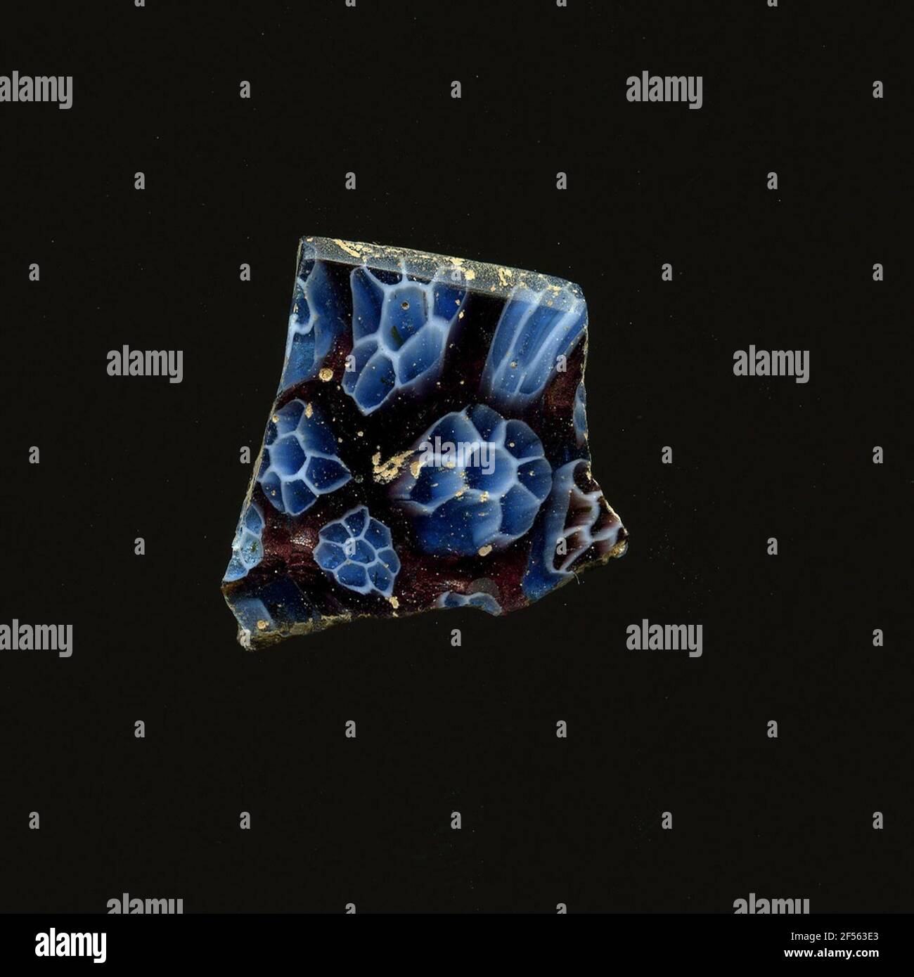 Fragment d'un vaisseau. Une faible courbure du fragment de verre permet l'affectation à un vaisseau, éventuellement à une coque. Le Blue Violet Shard montre plusieurs fleurs dans la technologie millefiori. Un contour blanc fin entoure un point bleu central et ses pétales. Pour la production, des verres de différentes couleurs ont été moulés dans des tubes et des tiges. Elles étaient comprimées et chauffées, ce qui entraînait une longue barre. Le verre coupé en tranches de ​​now avait des motifs amorphes ou floraux différents. Par la suite, plusieurs de ces plaquettes ont été repliées ensemble, réchauffées à nouveau et pressées en forme vasculaire. Burry pour le fabrici élaboré Banque D'Images