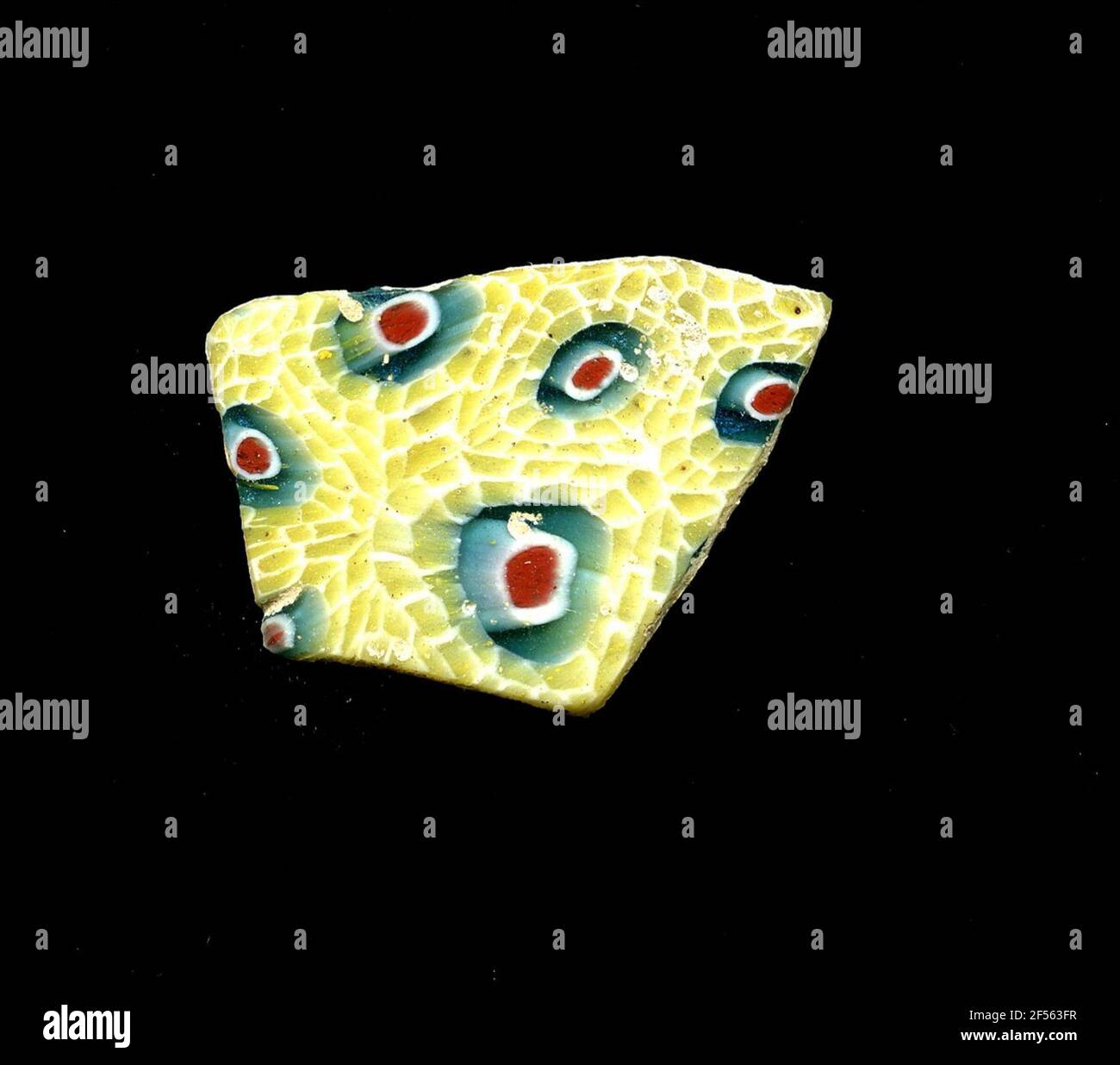 Fragment d'un vaisseau. Une faible courbure du fragment permet l'allocation à un vaisseau, éventuellement à une coque. Dans la technologie Millefiori, Blossom est floraison. À un noyau bleu rouge-blanc se trouvent dans une double rangée de pétales jaunes, qui sont entourés de blanc. Pour la production, des verres de différentes couleurs ont été façonnés sur des tubes et des tiges. Elles étaient comprimées et chauffées, ce qui entraînait une longue barre. Le ​​now en verre tranché avait une grande variété de motifs amorphes ou floraux. Par la suite, plusieurs de ces plaquettes ont été repliées ensemble, réchauffées à nouveau et pressées en forme vasculaire. Burry pour la proce de fabrication élaborée Banque D'Images