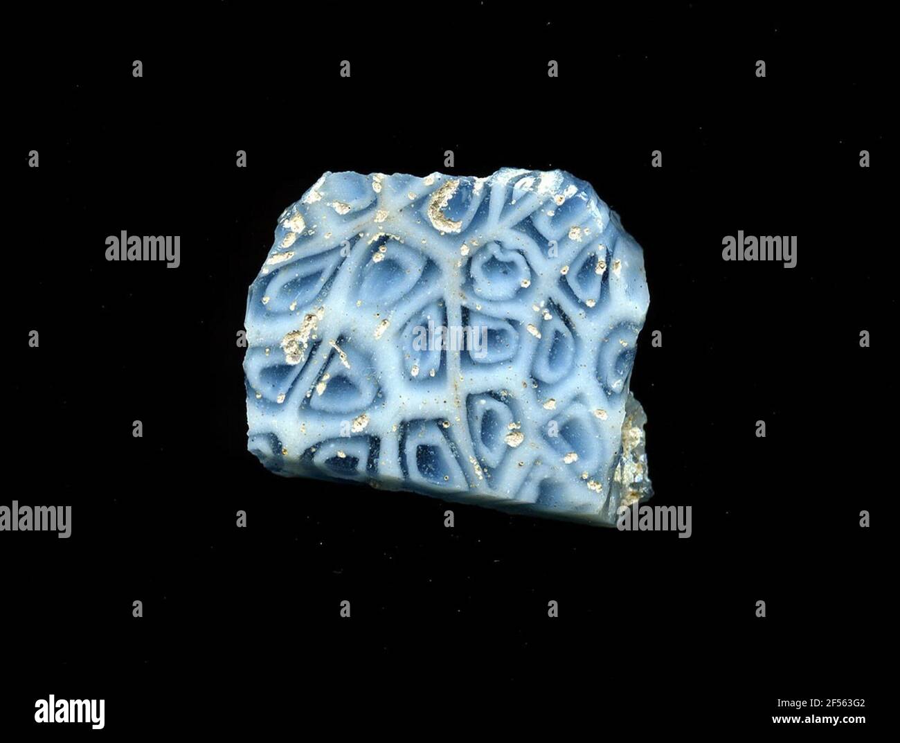 Fragment d'un vaisseau. Une faible courbure du fragment de verre permet l'affectation à un vaisseau, éventuellement à une coque. Sur fond blanc, plusieurs formes polygonales bleues avec bordure bleue peuvent être vues, ce qui devrait faire des fleurs. Pour la production, des verres de différentes couleurs ont été formés en tubes et en tiges. Elles étaient comprimées et chauffées, ce qui entraînait une longue barre. Le ​​now en verre tranché avait une grande variété de motifs amorphes ou floraux. Par la suite, plusieurs de ces plaquettes ont été repliées ensemble, réchauffées à nouveau et pressées en forme vasculaire. Burry pour le processus de fabrication élaboré et sa fra Banque D'Images