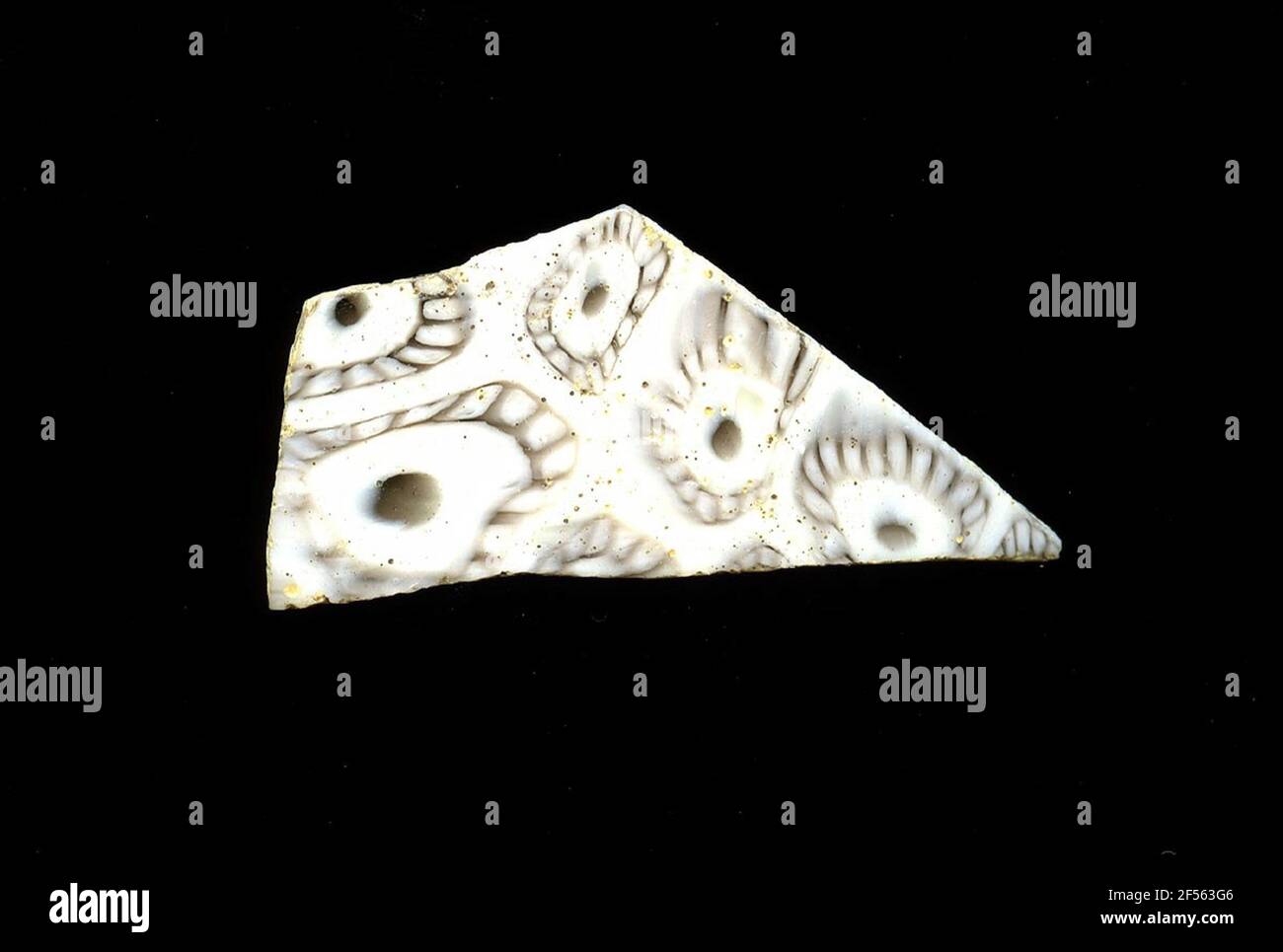 Fragment d'un vaisseau. Une faible courbure du fragment de verre permet l'affectation à un vaisseau, éventuellement à une coque. Sur fond blanc, plusieurs fleurs sont visibles dans la technologie millefiori. Ils se composent d'un point marron à reconnaître sur une ligne circulaire de plusieurs pétales avec un contour marron. Pour la production, des verres de différentes couleurs ont été moulés dans des tubes et des tiges. Elles étaient comprimées et chauffées, ce qui entraînait une longue barre. Le verre coupé en tranches de ​​now avait des motifs amorphes ou floraux différents. Par la suite, plusieurs de ces plaquettes ont été repliées ensemble, réchauffées à nouveau et pressées en forme vasculaire Banque D'Images