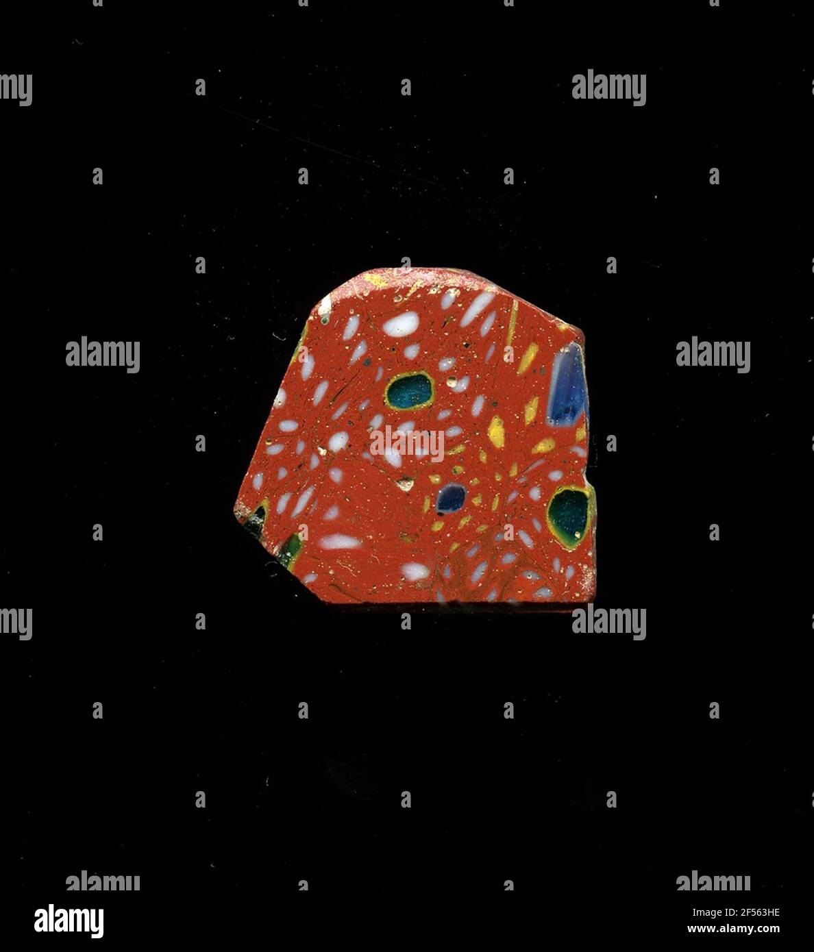 Fragment d'un vaisseau. Une faible courbure du fragment de verre permet l'affectation à un vaisseau, éventuellement à une coque. Sur le fragment rouge, plusieurs fleurs sont représentées dans la technologie millefiori. De nombreux petits points jaunes ou blancs entourent un point plus grand, soit vert avec un contour jaune, soit bleu avec un contour blanc. Pour la production, des verres de différentes couleurs ont été façonnés en tubes et en tiges. Elles étaient comprimées et chauffées, ce qui entraînait une longue barre. Le verre coupé en tranches de ​​now avait des motifs amorphes ou floraux différents. Par la suite, plusieurs de ces plaquettes ont été repliées ensemble, réchauffées à nouveau et pressées dans le système vasculaire Banque D'Images