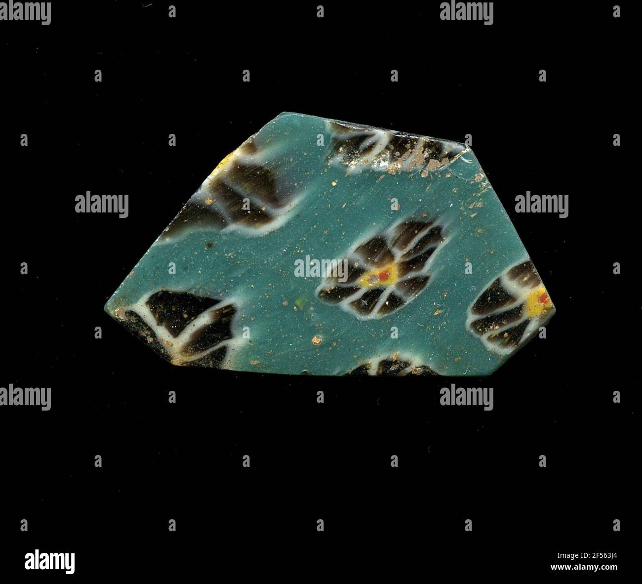 Fragment d'un vaisseau. Une faible courbure du fragment de verre permet l'affectation à un vaisseau, éventuellement à une coque. Sur la raison turquoise, plusieurs fleurs dans la technologie millefiori peuvent être vues. Les fleurs individuelles se composent d'un point rouge avec une bordure jaune comme noyau pour poser les points bruns avec contour blanc comme pétales. Pour la production, des verres de différentes couleurs ont été formés en tubes et en tiges. Elles étaient comprimées et chauffées, ce qui entraînait une longue barre. Le verre coupé en tranches de ​​now avait des motifs amorphes ou floraux différents. Par la suite, plusieurs de ces plaquettes ont été pliées ensemble, réchauffées à nouveau et pressées Banque D'Images
