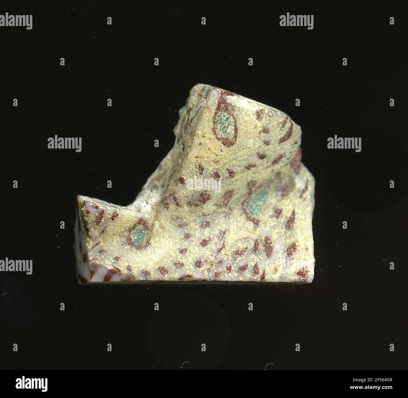 Fragment d'un vaisseau. Une faible courbure du fragment de verre permet l'affectation à un vaisseau, éventuellement à une coque. Le verre blanc montre plusieurs ornements de fleurs dans la technologie millefiori. Pour créer un point turquoise avec un contour rouge, découpez de petits points rouges à une certaine distance que les pétales. Pour la production, des verres de différentes couleurs ont été formés en tubes et en tiges. Elles étaient comprimées et chauffées, ce qui entraînait une longue barre. Le verre coupé en tranches de ​​now avait des motifs amorphes ou floraux différents. Par la suite, plusieurs de ces plaquettes ont été repliées ensemble, réchauffées à nouveau et pressées en forme vasculaire. Burry pour Banque D'Images