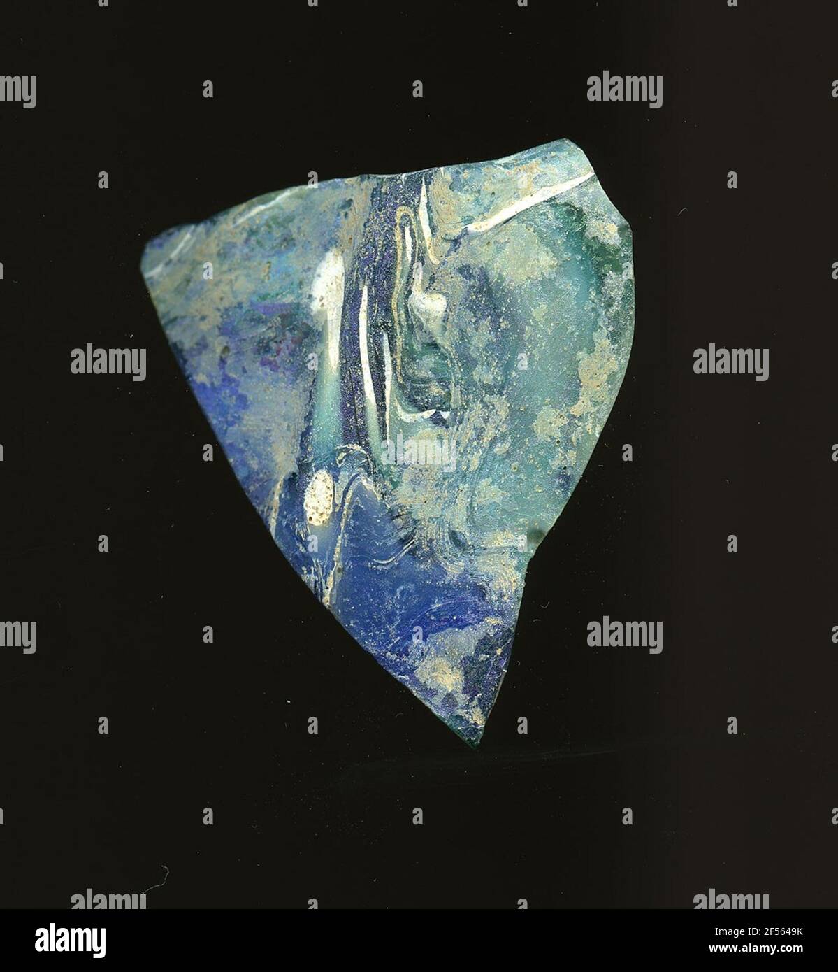 Fragment d'une coque de nervure. À l'extérieur du fragment de verre se trouve une nervure, qui permet une affectation à un vaisseau, éventuellement une coque. Le verre est marbré de l'obscurité sur bleu clair à turquoise et blanc. Un point rouge se trouve à l'intérieur. Pour la production, des verres de différentes couleurs ont été formés en tubes et en tiges. Elles étaient comprimées et chauffées, ce qui entraînait une longue barre. Le verre coupé en tranches de ​​now avait des motifs amorphes ou floraux différents. Par la suite, plusieurs de ces plaquettes ont été repliées ensemble, réchauffées à nouveau et pressées en forme vasculaire. Burry pour la proce de fabrication élaborée Banque D'Images