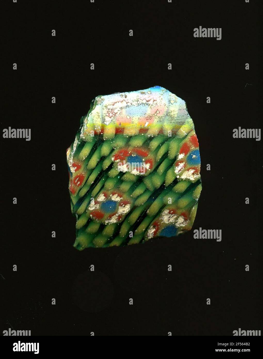 Fragment d'un vaisseau. Une faible courbure du fragment de verre permet l'affectation à un vaisseau, éventuellement à une coque. Sur le shard vert, plusieurs fleurs peuvent être vues dans la technologie millefiori. Sur un point bleu avec un contour jaune, des points rouges à bords jaunes sont attachés sous forme de pétales. Ils sont entourés de points jaunes sur des lignes circulaires. Pour la production, des verres de différentes couleurs ont été formés en tubes et en tiges. Elles étaient comprimées et chauffées, ce qui entraînait une longue barre. Le verre coupé en tranches de ​​now avait des motifs amorphes ou floraux différents. Par la suite, plusieurs de ces plaquettes ont été repliées ensemble, chauffé à nouveau un Banque D'Images