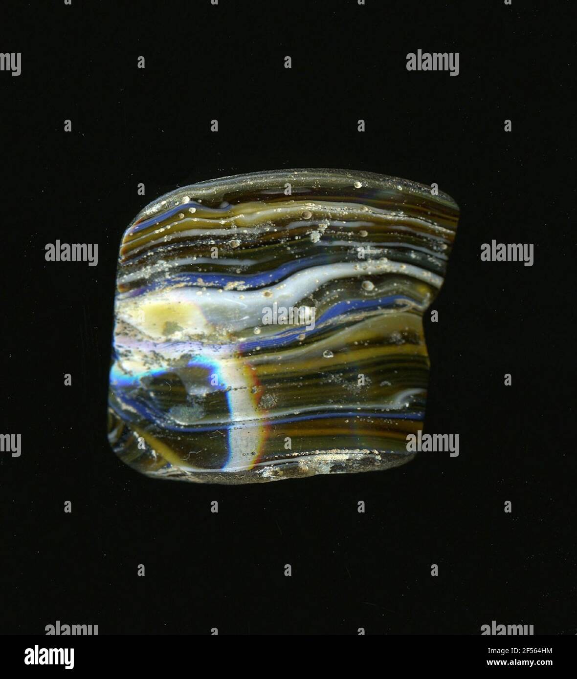 Fragment d'un vaisseau. Une faible courbure du fragment de verre permet l'affectation à un vaisseau, éventuellement à une coque. En raison du verre clair à brun foncé, les fines rayures blanches et bleues sont irrégulières. Pour la production, des verres de différentes couleurs ont été formés en tubes et en tiges. Elles étaient comprimées et chauffées, ce qui entraînait une longue barre. Le ​​glass maintenant coupé avait des modèles différents. Par la suite, plusieurs de ces plaquettes ont été repliées ensemble, réchauffées à nouveau et pressées en forme vasculaire. Burry pour le processus de fabrication élaboré et sa fragilité a été l'un des articles de luxe de l'antiquité. Banque D'Images