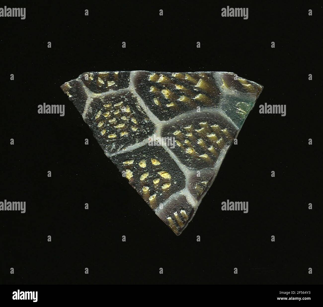 Fragment d'un vaisseau. Une faible courbure du fragment de verre permet l'affectation à un vaisseau. Le verre brun foncé est traversé par une grille de lignes blanches rappelant les nids d'abeilles. Dans les champs, il y a des fleurs dans la technologie millefiori, qui se composent de points jaunes circulaires. Pour la production, différentes verres de couleur aux tubes et tiges ont été formés. Elles étaient comprimées et chauffées, ce qui entraînait une longue barre. Le verre coupé en tranches de ​​now avait des motifs amorphes ou floraux différents. Par la suite, plusieurs de ces plaquettes ont été fusionnées, réchauffées à nouveau et formées. Burry pour le processus de fabrication élaboré Banque D'Images