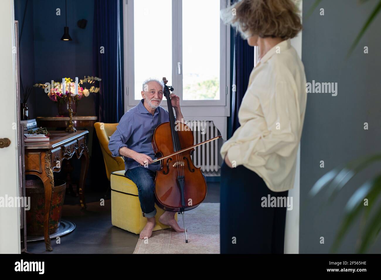 Homme souriant regardant une femme en jouant au violoncelle à la maison Banque D'Images