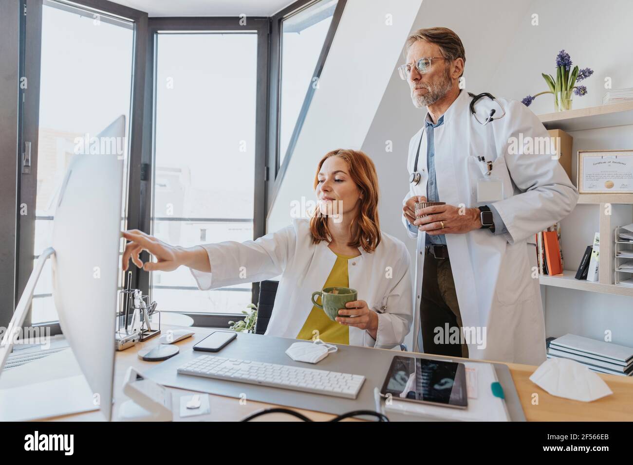 Les médecins prenant un café tout en travaillant sur ordinateur à la clinique Banque D'Images