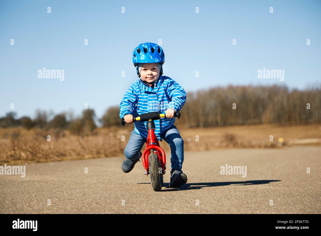 Mignon garçon portant un casque de cyclisme à vélo pendant la journée ensoleillée sur route Banque D'Images