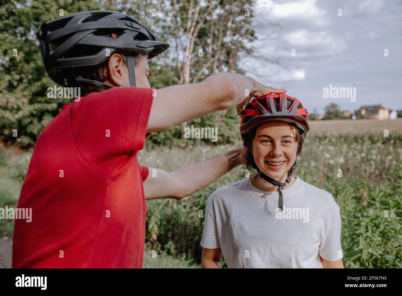 Père aidant fille porter un casque de cyclisme Banque D'Images