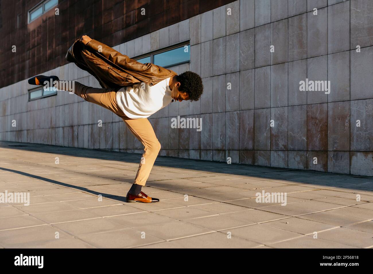 Danseur dansant sur une jambe contre le bâtiment Banque D'Images