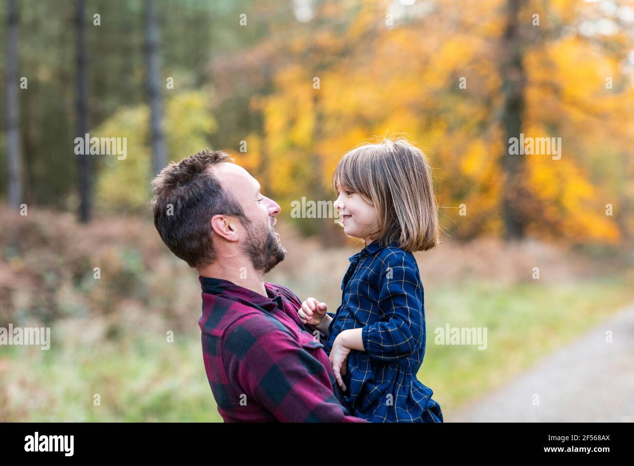 Père portant sa fille dans les bras en étant debout dans la forêt Banque D'Images