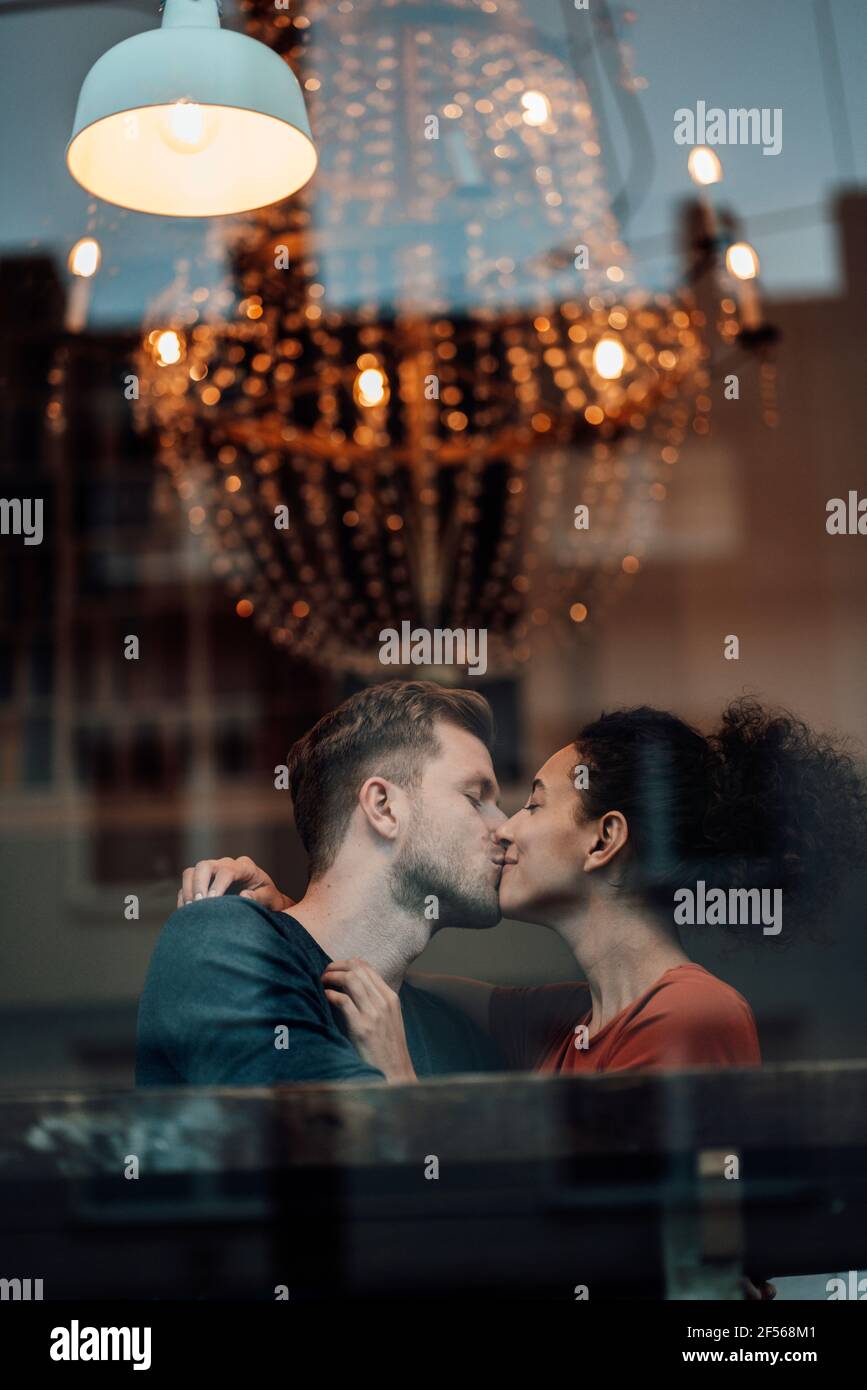 Petit ami et petite amie s'embrassant tout en étant assis au café Banque D'Images