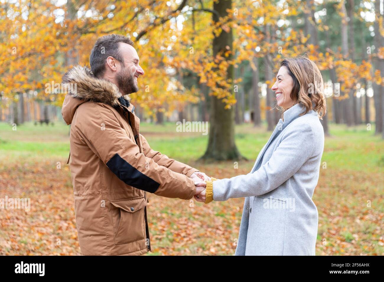 Couple souriant tenant les mains en forêt Banque D'Images