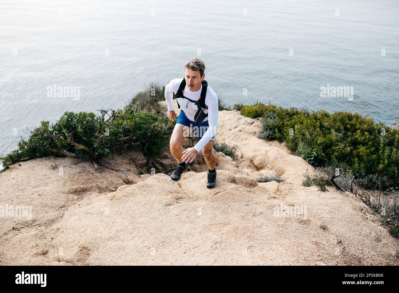 Homme déterminé courant sur des rochers près de la mer Banque D'Images