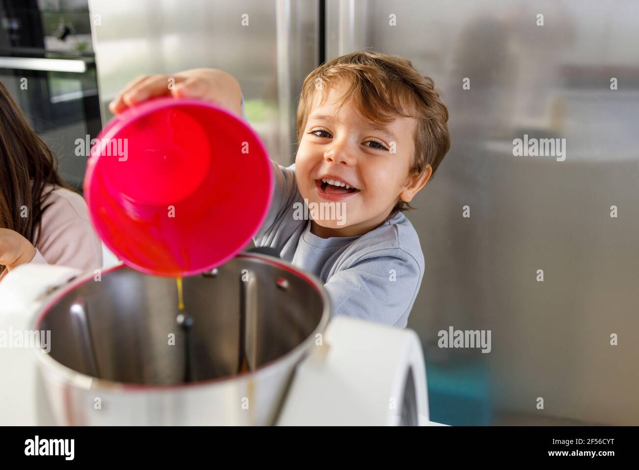 Curieux garçon par sœur cassant l'œuf dans le bol à mélanger au comptoir de cuisine Banque D'Images